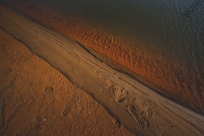 Brown sand near water during the day
